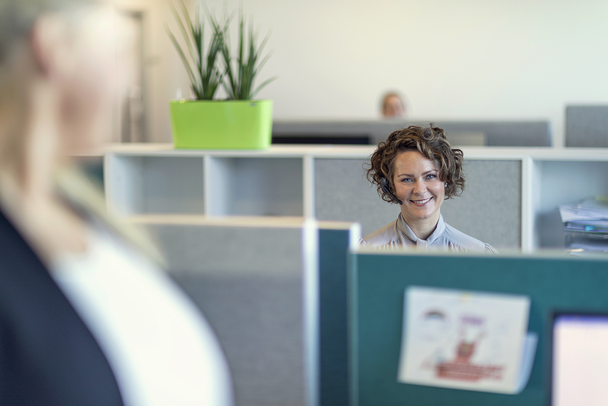 Kvinde sidder på kontor med headset 