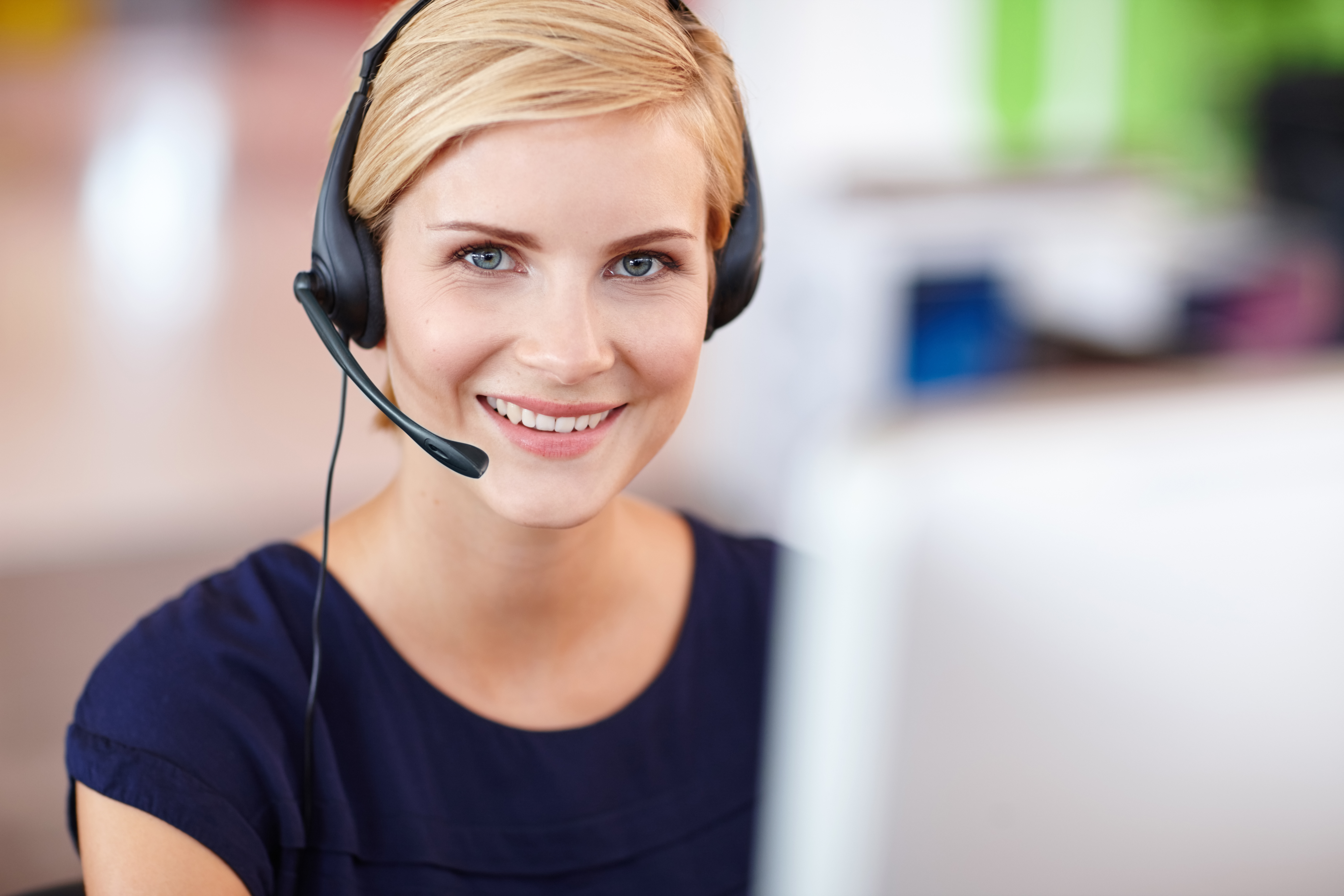 kvinde der smiler med headset på arbejde
